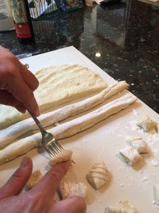 Pressing cubes of dough against the fork for the unique gnocchi shape and texture